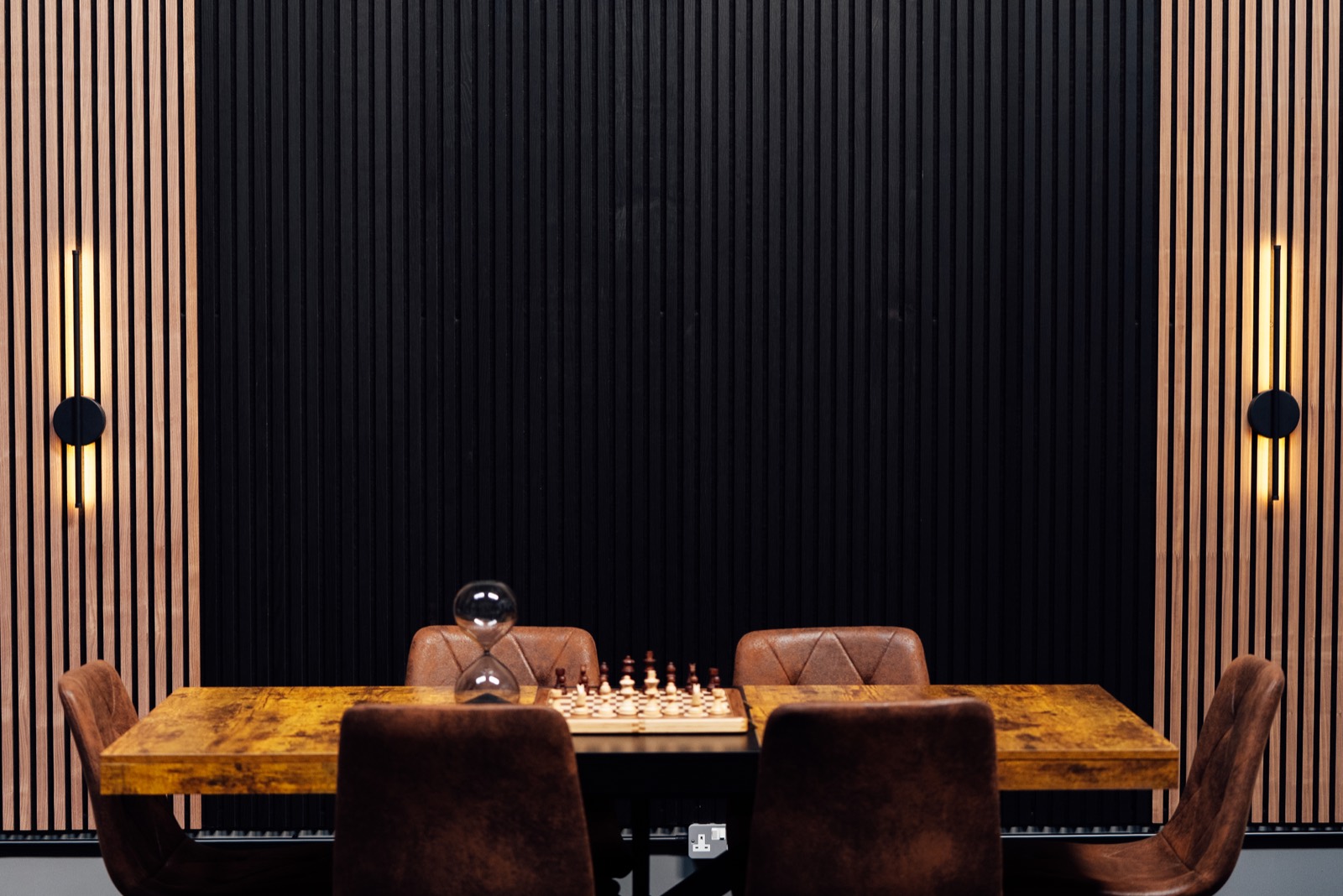 Chess table and chairs in front of the timber slat wall