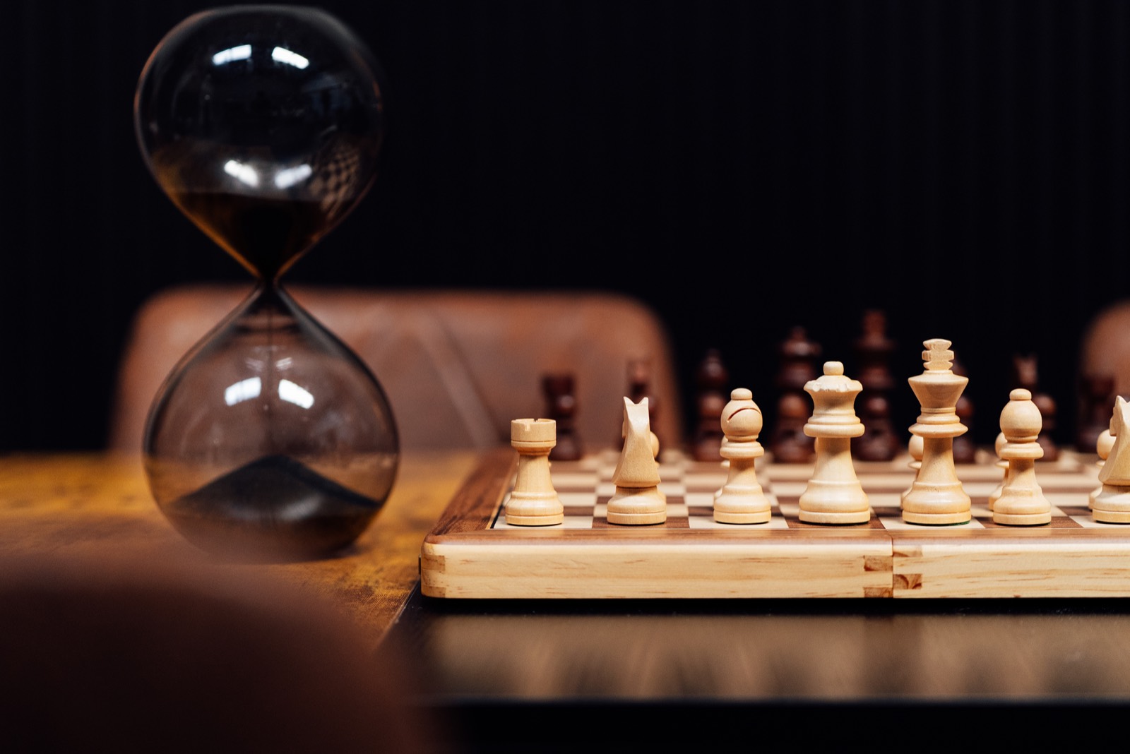 Chess pieces with hourglass on the table