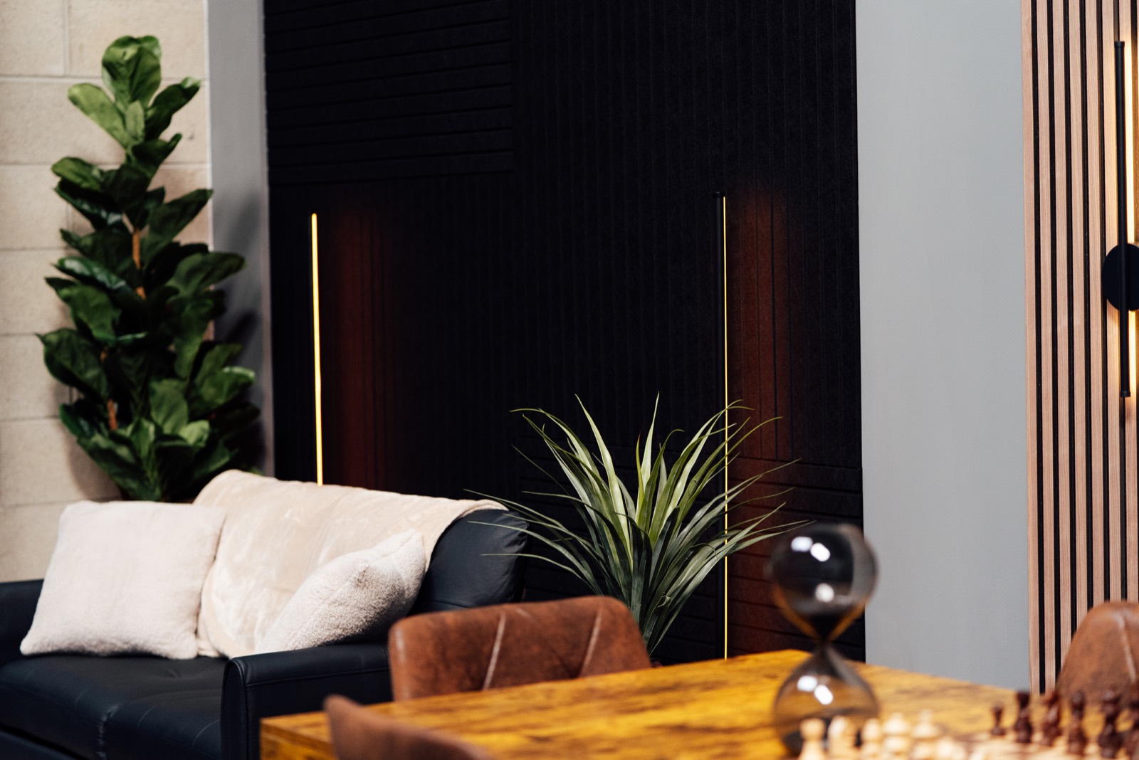 Studio lounge with sofa, plants, timber wall light and chess table