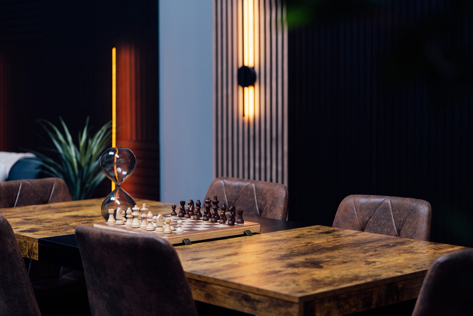 Chess table with hourglass, leather chairs and linear lighting