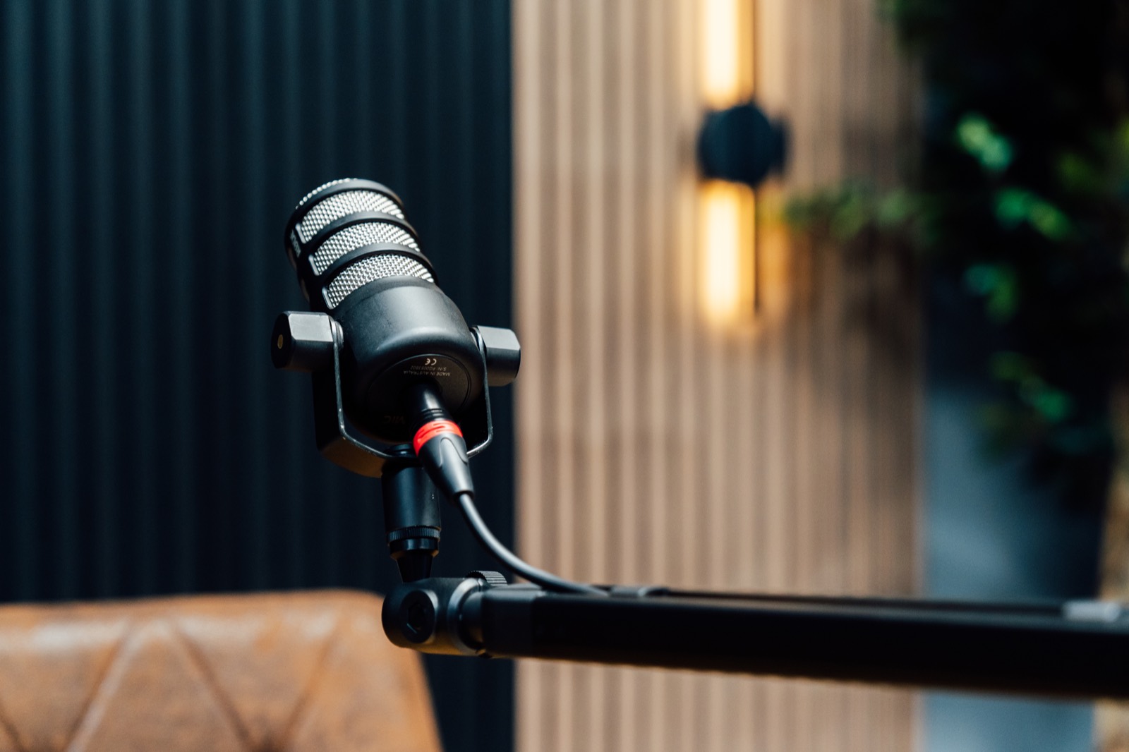 RØDE PodMic on a boom arm against the timber slat wall