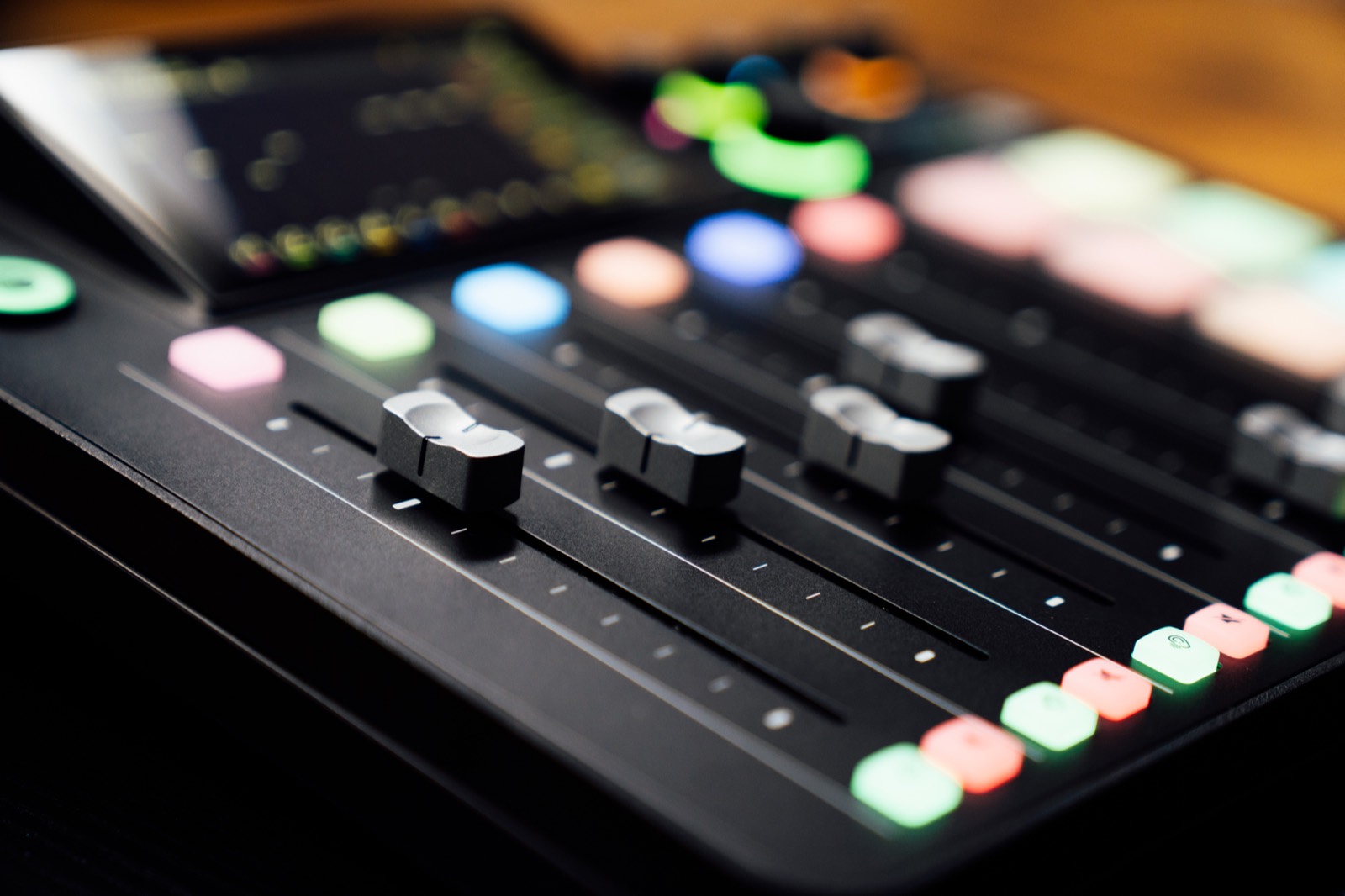 Close-up of mixer faders and backlit controls